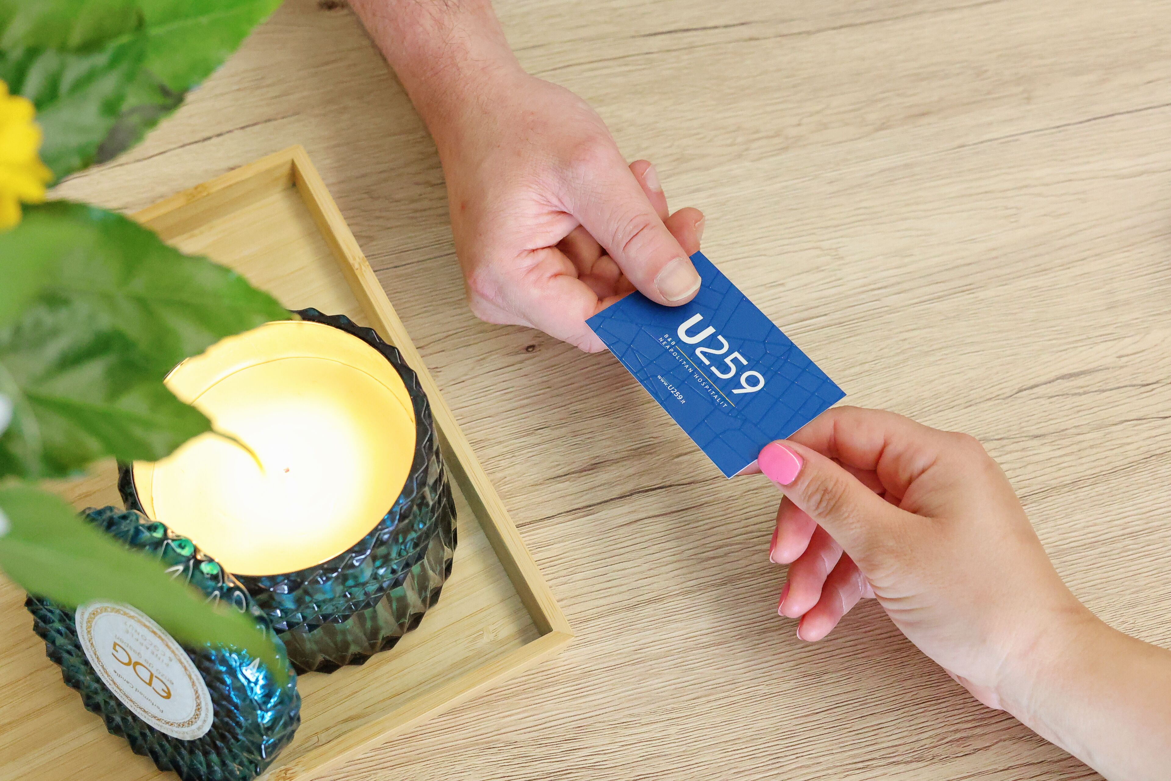 A hand holding a card labeled "U259" next to a candle in a decorative holder.