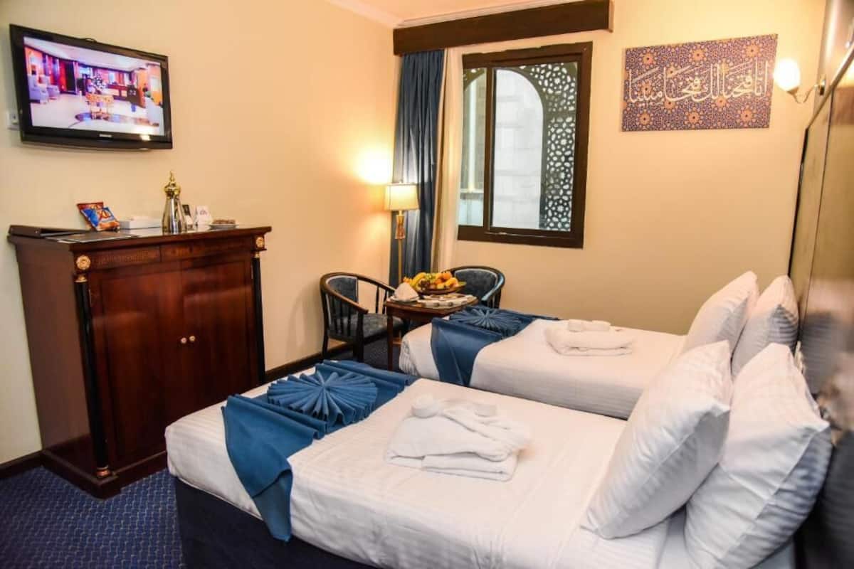Une chambre d’hôtel avec deux lits, un bureau, une télévision et une fenêtre donnant sur un paysage agréable.