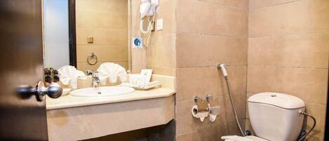 A bathroom with a sink, mirror, hairdryer, and toilet.