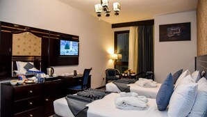Hotellihuone, jossa on kaksi sänkyä, työpöytä, televisio ja kattokruunu.