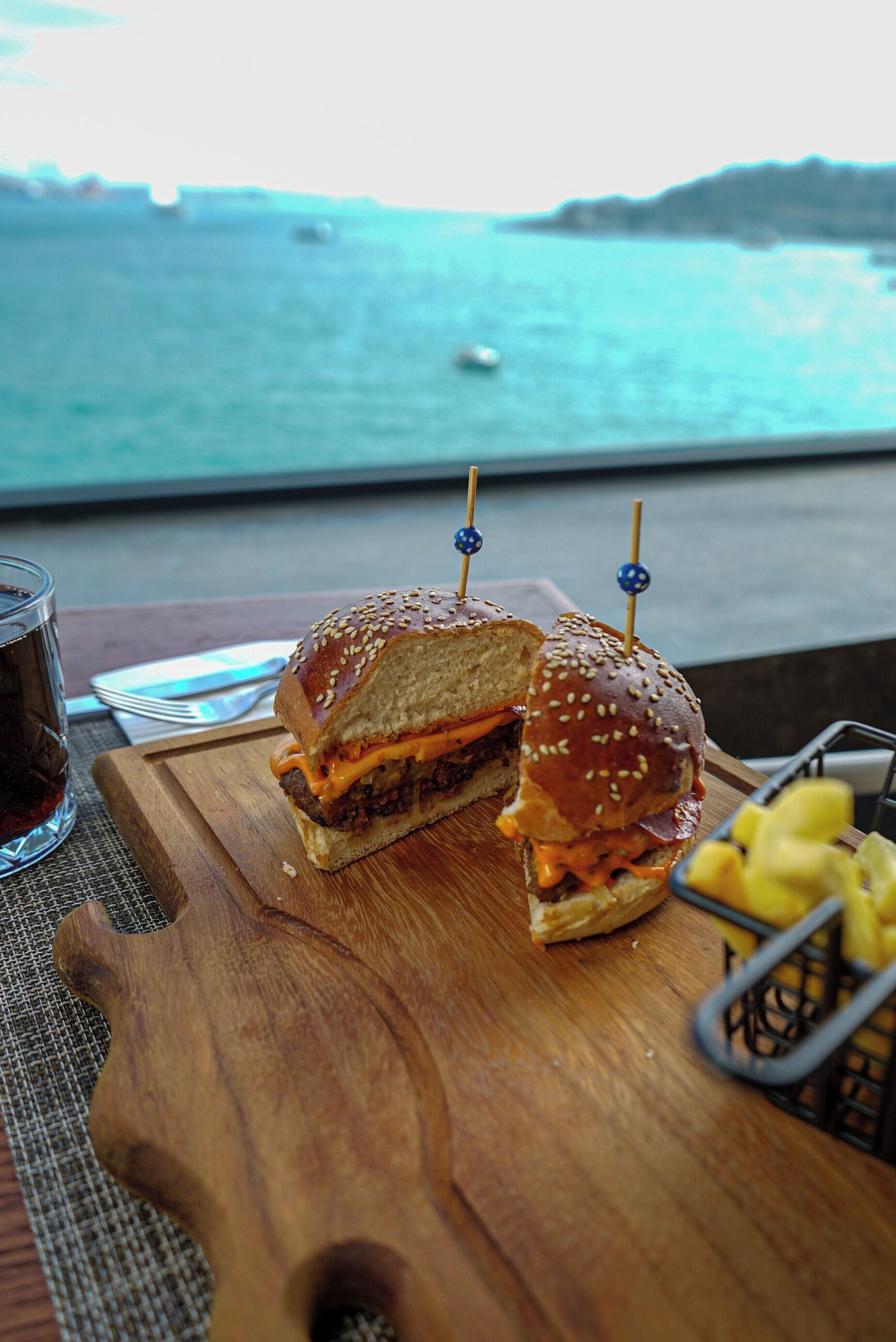 Un sandwich servi sur une planche en bois, avec la mer en toile de fond.
