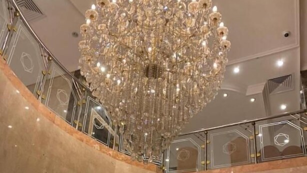 A multi-level hotel lobby with a grand chandelier, marble flooring, and a modern elevator area. - Plaza Inn Ohud (Madinah)