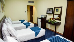 A hotel room with four beds, a desk with a coffee maker, and a small refrigerator. - Plaza Inn Ohud (Madinah)