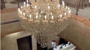 A grand chandelier with multiple candles, a reception desk, and a geometric floor design. - Plaza Inn Ohud (Madinah)