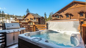 A wooden cabin with a hot tub and a Weber Genesis grill.