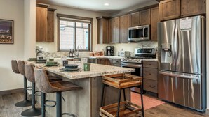 A modern kitchen with wooden cabinets, stainless steel appliances, and a central island with bar stools.