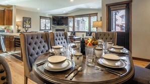 A dining area with a round table set for four, surrounded by tufted chairs.