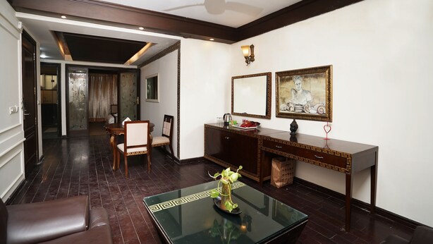 A modern living room with a glass coffee table, a dining area with a wooden table and chairs, a dark wooden cabinet, and a ceiling fan. - Lyf Corporate Suites. New Friends Colony (New Delhi)