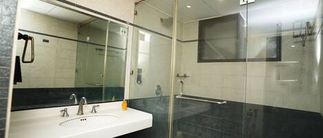 A modern bathroom with a glass-enclosed shower, a white sink, and a large mirror.