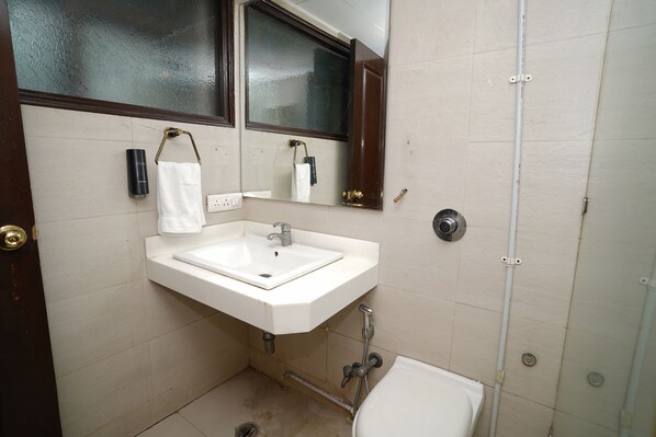 Une salle de bain avec un lavabo blanc, un miroir, une serviette et des toilettes.