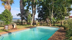 Una piscina envoltada d'arbres i una tanca de fusta.