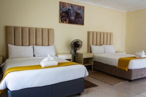 A hotel room with two beds, a fan, and a bull painting on the wall.