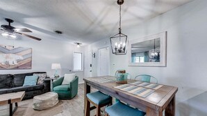 A modern living room with a sofa, coffee table, and a dining table with chairs. - River's Song Condo- Convenient for Walking (Helen)