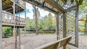 A wooden swing set with a chain, a wooden bench, and a wooden pergola structure. - River's Song Condo- Convenient for Walking (Helen)