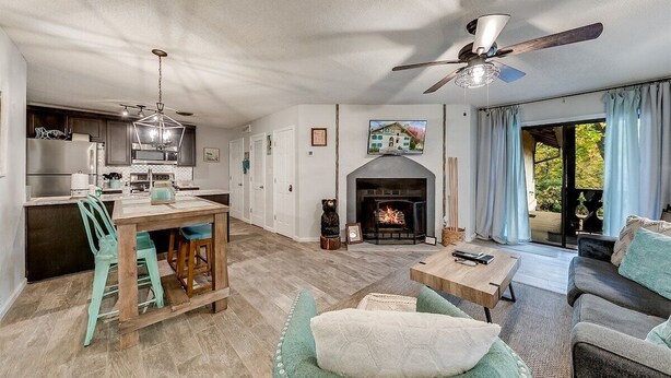 A spacious living area with a fireplace, a dining table, and a sofa. - River's Song Condo- Convenient for Walking (Helen)