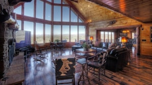 A rustic lodge interior with a large fireplace, leather seating, and a stone wall with mounted animal heads. - Five Star Lodge and Stables is pet friendly with a big mountain view. hot tub, firepits. Ideal for Weddings and Corporate Retreats (Morganton)