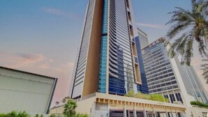 Un immeuble moderne de grande hauteur, doté d’un design architectural unique, caractérisé par un élément vertical marquant et une combinaison de façades en verre et en béton.