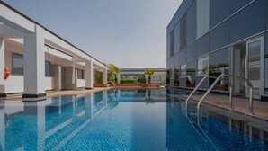 Une piscine intérieure moderne, avec une eau d’un bleu limpide, entourée d’une architecture contemporaine et sous un ciel dégagé.