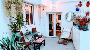 A small patio area with a table and chairs, surrounded by potted plants. - ღ LE JARDIN PARISIEN - quiet with terrace wifi, video projector (Paris)