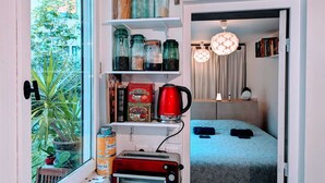 A compact kitchen with a toaster, a red kettle, and various jars on shelves. - ღ LE JARDIN PARISIEN - quiet with terrace wifi, video projector (Paris)