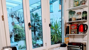 A kitchen with white cabinets, a fruit bowl, a calendar, and a red coffee maker. - ღ LE JARDIN PARISIEN - quiet with terrace wifi, video projector (Paris)