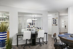 A modern dining area with a central table, chairs, and a large mirror.