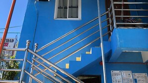 A blue building with a metal staircase and a window. - RAVARA-NATIVIDAD PENSION HOUSE (Alaminos)
