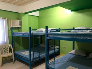 A dormitory room with bunk beds, a white plastic chair, and an air conditioning unit. - RAVARA-NATIVIDAD PENSION HOUSE (Alaminos)