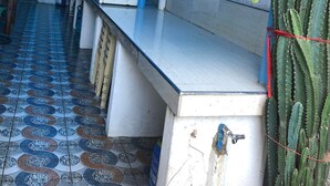 A narrow corridor with a tiled floor, a counter with a sink, and a hanging plant. - RAVARA-NATIVIDAD PENSION HOUSE (Alaminos)