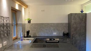 Una cocina moderna con una isla grande, electrodomésticos integrados y una planta colgante.