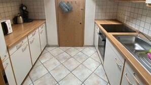 A compact kitchen with a skylight, tiled floor, and wooden cabinets. - Schöne Ferienwohnung "hubertus" im Dachgeschoss (Holzkirchen)