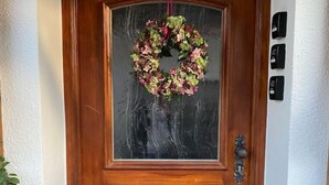 A wooden front door with a heart-shaped wreath, a glass panel, and a metal knocker. - Schöne Ferienwohnung "hubertus" im Dachgeschoss (Holzkirchen)