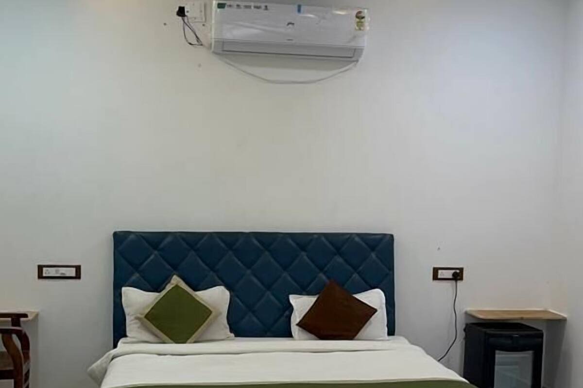 Un dormitorio con cama, ventilador de techo, aire acondicionado y mesita de noche.
