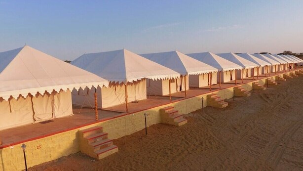 A row of white tents with steps leading up to them, set on sandy ground. - Gujarat Resort Jaisalmer (Jaisalmer)
