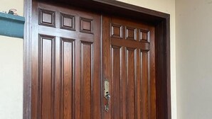 Una puerta doble de madera con diseño tradicional, un picaporte metálico y un acceso con tejas rojas.