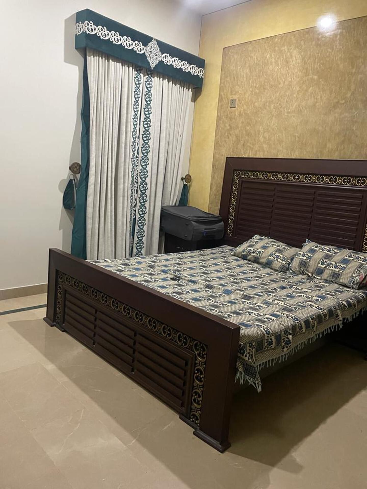 Un dormitorio con cama, cortinas, mesita de noche y pared con textura.