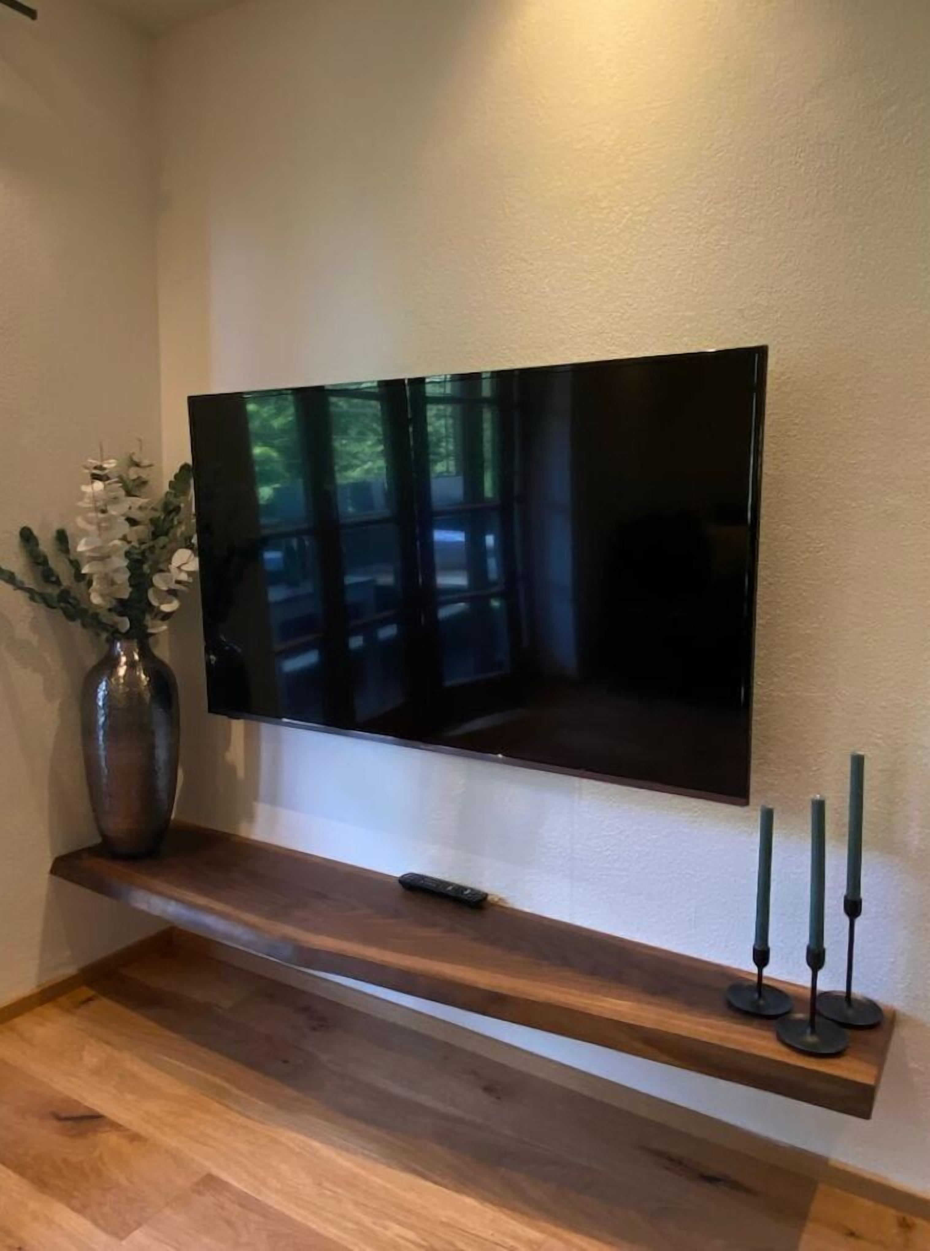 Ein Flachbildfernseher an der Wand über einem Holzregal.