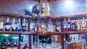 A bar with multiple shelves of liquor bottles and glasses. - Sarge's Hotel (Serrekunda)