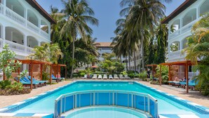 A pool area with lounge chairs and palm trees. - Sarge's Hotel (Serrekunda)