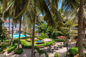 Patio de un resort con piscina, palmeras y zonas de estar al aire libre.