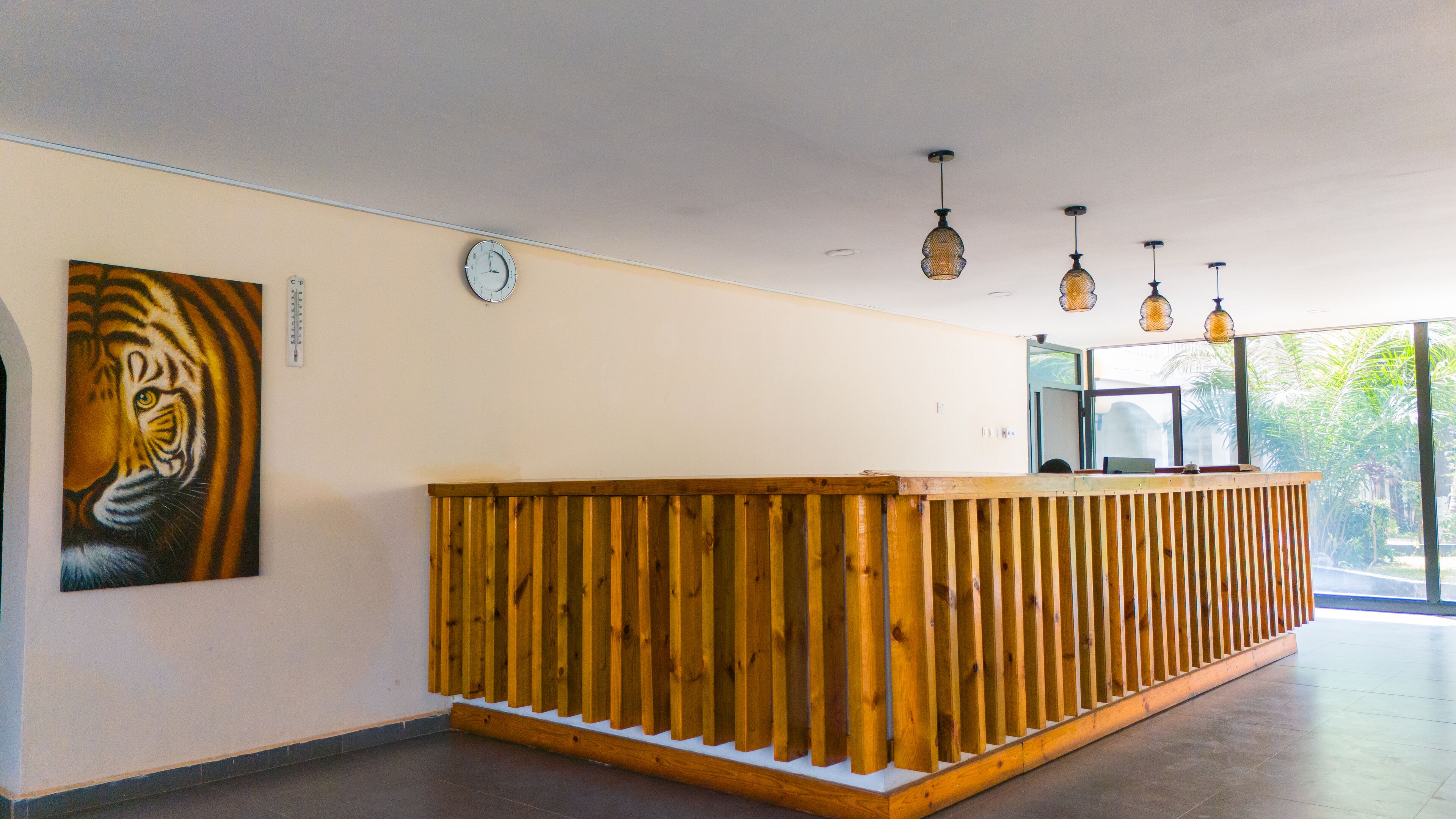 Un mostrador de recepción con diseño de listones de madera, un reloj en la pared e iluminación colgante.
