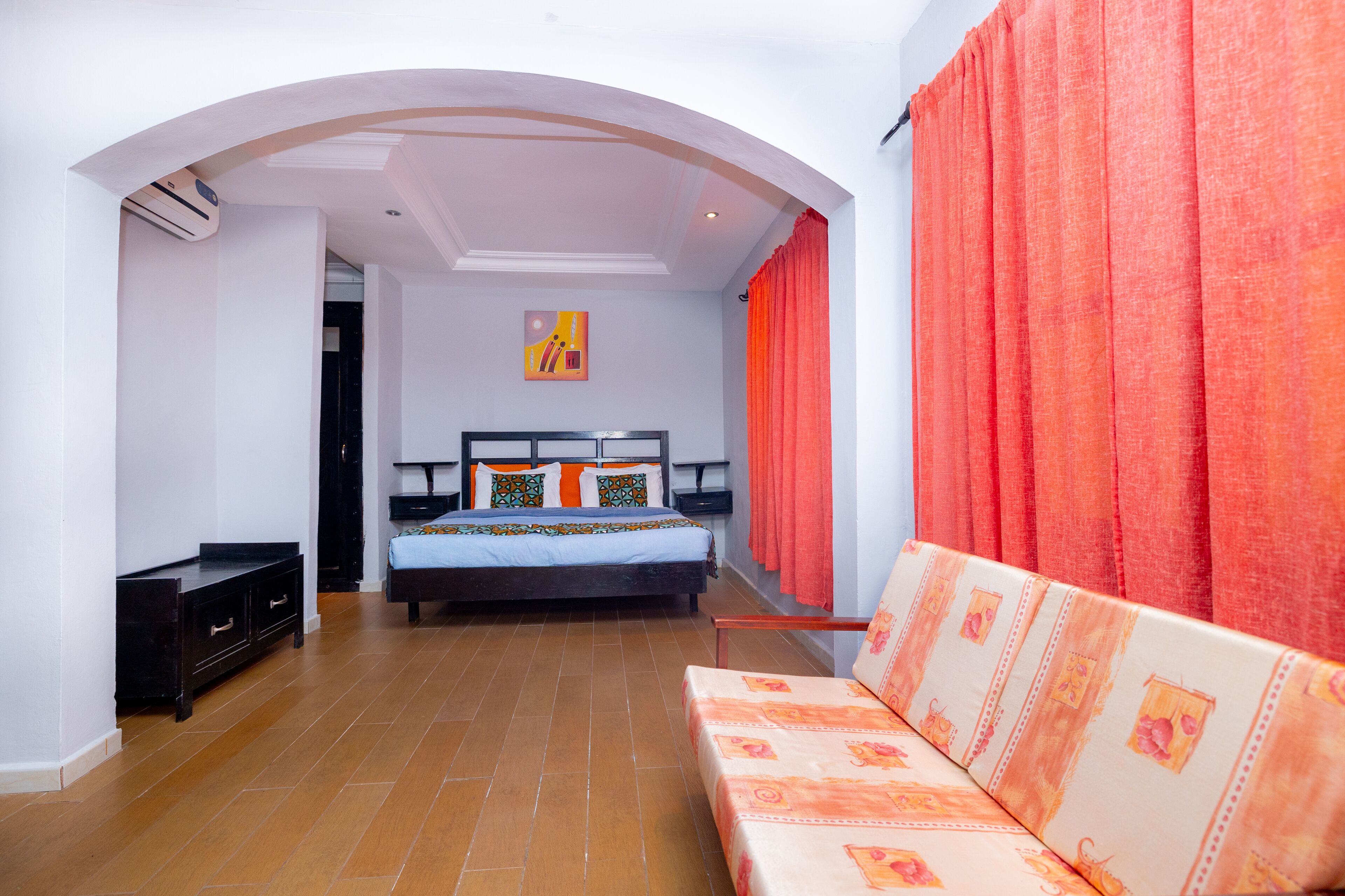 Una camera da letto con un letto, un divano, una cassettiera e un quadro appeso al muro.