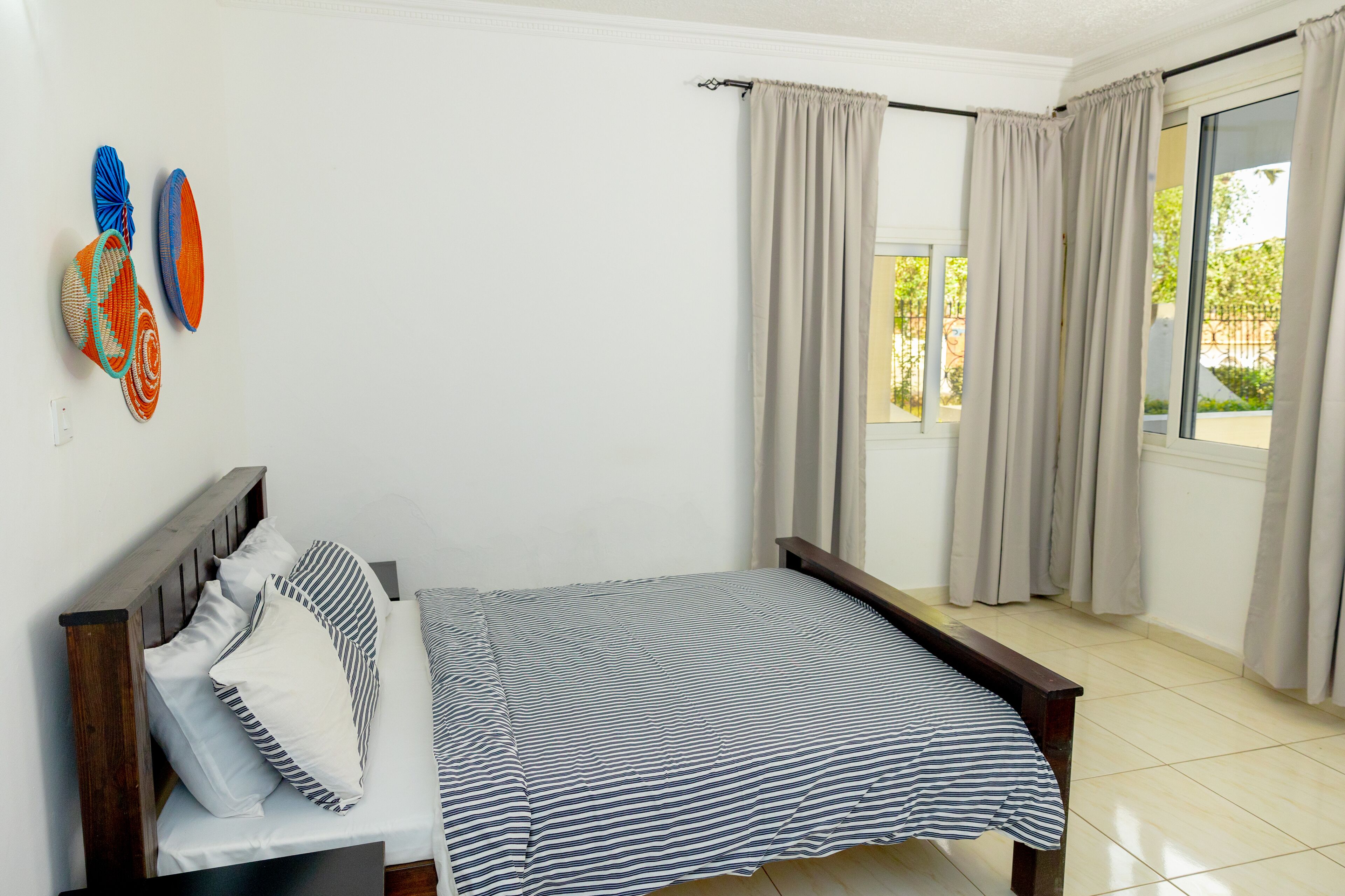 A bedroom with a bed, curtains, and a window.