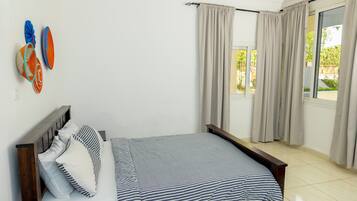 A bedroom with a bed, curtains, and a window.