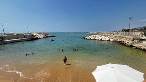 A beach with clear water, a rocky breakwater, and a few people swimming. - Duplex at Solemar resort, totally renovated, pools, tennis, basketball, football (Kaslik)