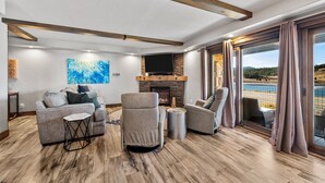 A spacious living room with a fireplace, comfortable seating, and a large window offering a scenic view.