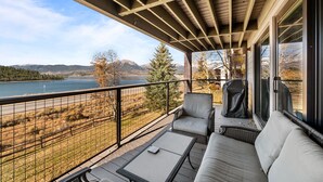 A balcony with a view of a lake, surrounded by trees and mountains.
