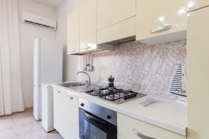 Una cocina compacta con estufa a gas, horno y refrigerador.