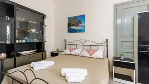 Een keurig opgemaakt hotelkamer met een bed, een garderobe, een nachtkastje en een aan de muur hangend schilderij.