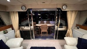 A yacht interior with a dining area, two sofas, and a view of the night sky. - Superyacht on 5* Town Quay Marina, Southampton (Southampton)